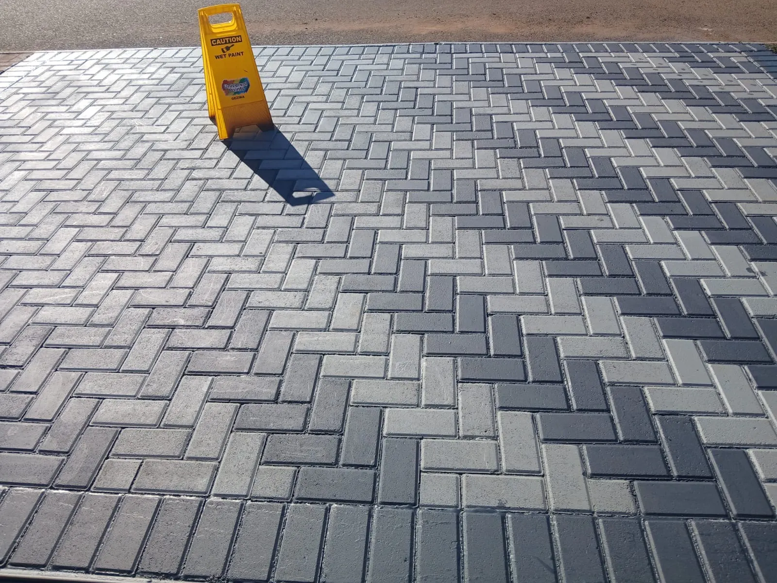 Freshly painted charcoal herringbone paving showing clean professional finish