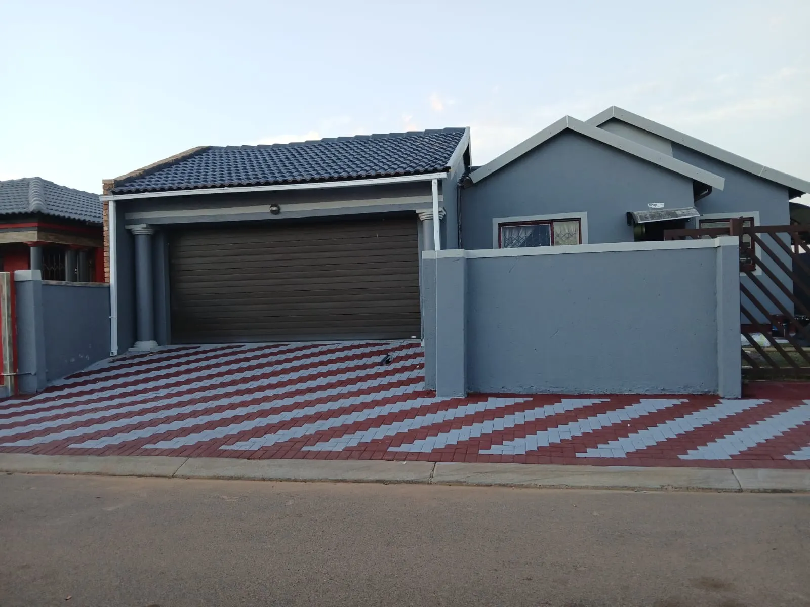 House exterior before and after comparison showing an unpainted wall and a blue-grey finish - after