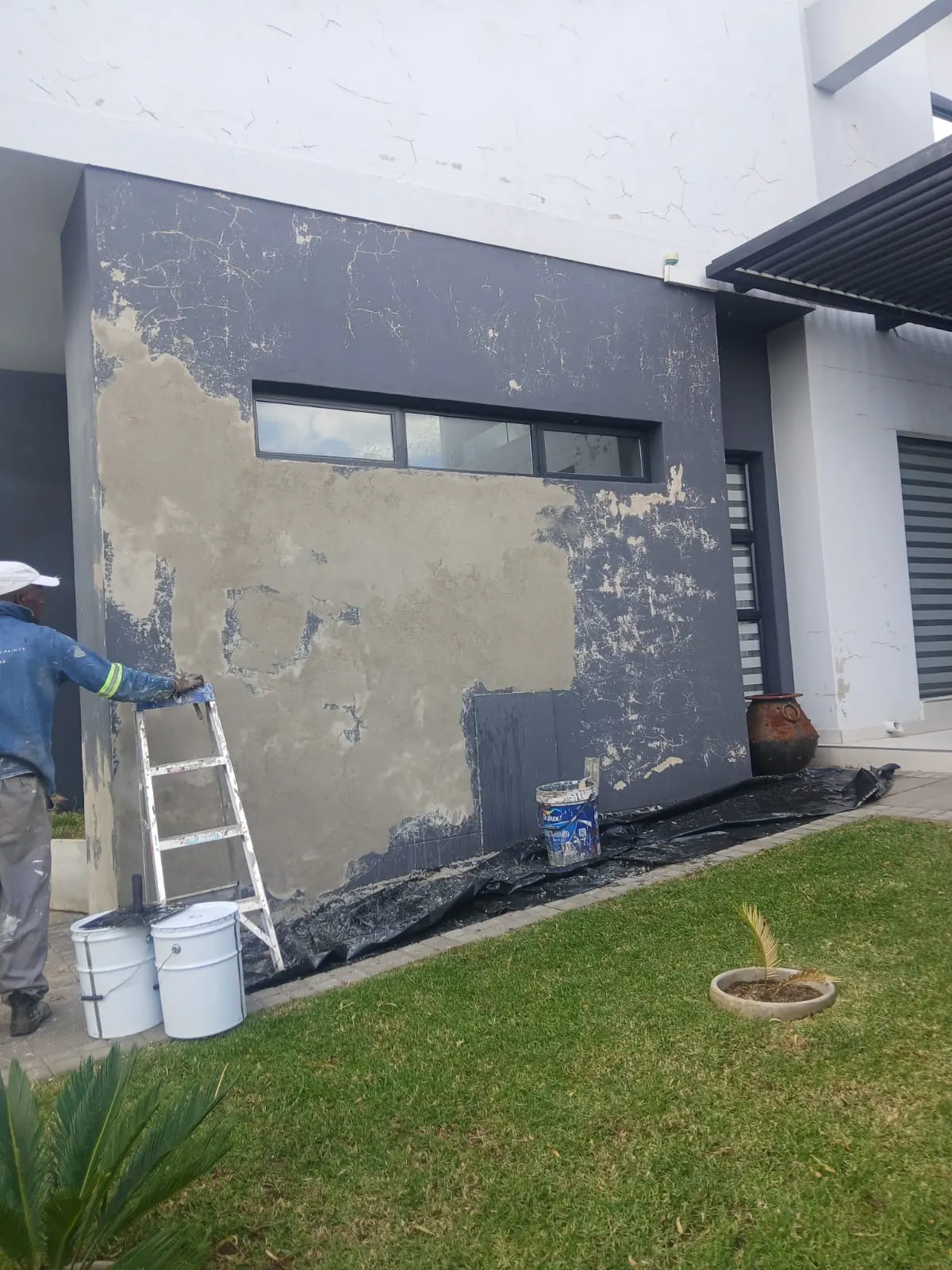 House exterior before and after comparison showing a change from a worn wall to a painted finish - before