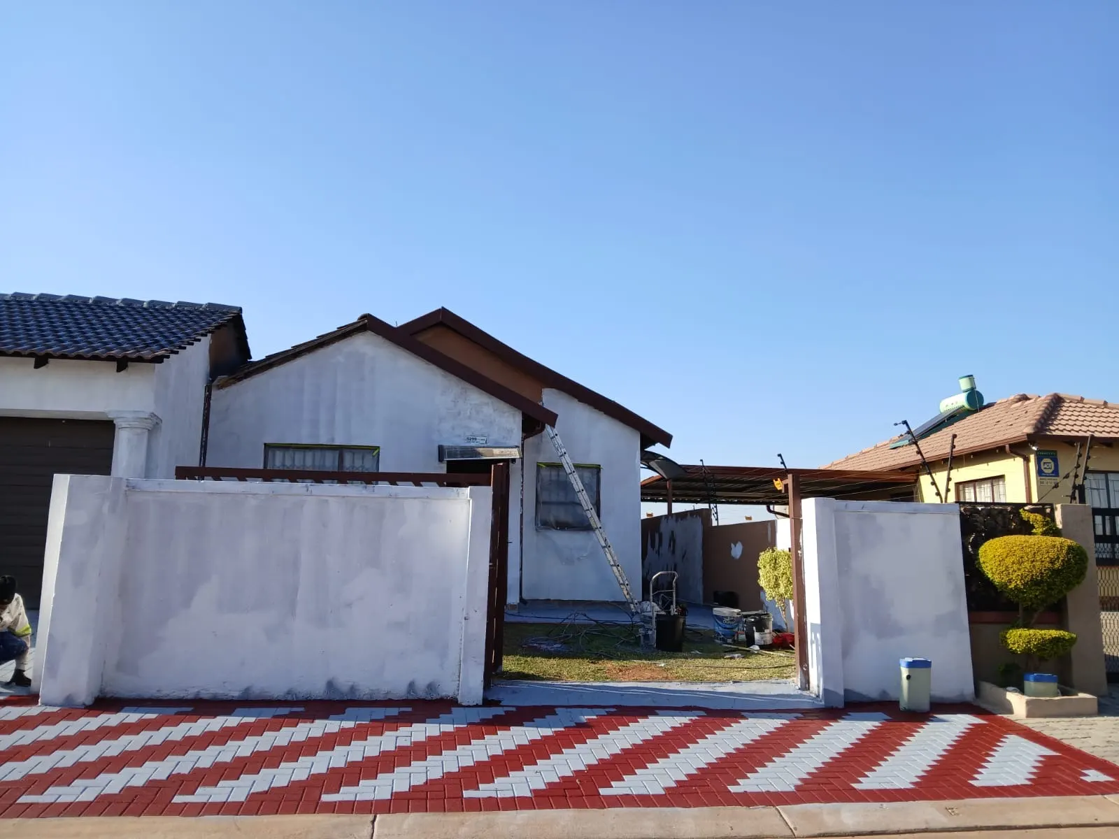 House exterior before and after comparison showing an unpainted wall and a blue-grey finish - before
