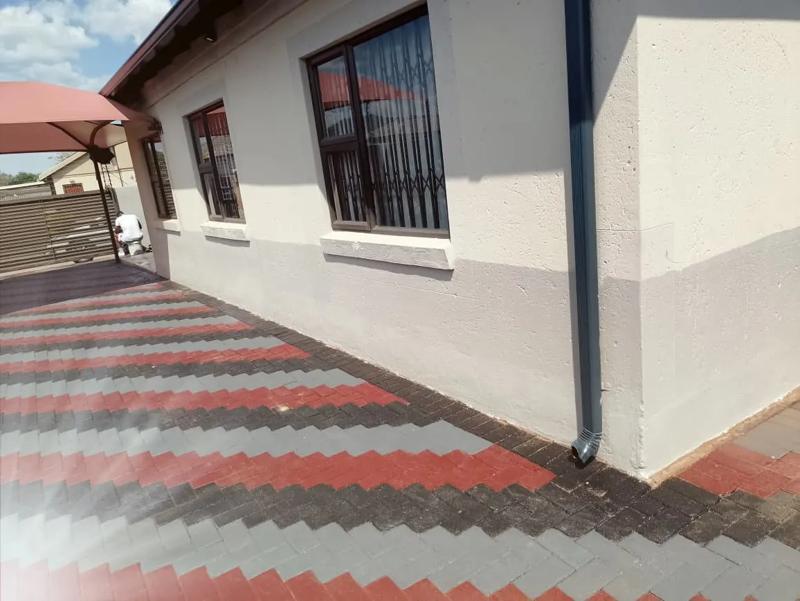 Paving beside a house painted in red, grey and charcoal stripes