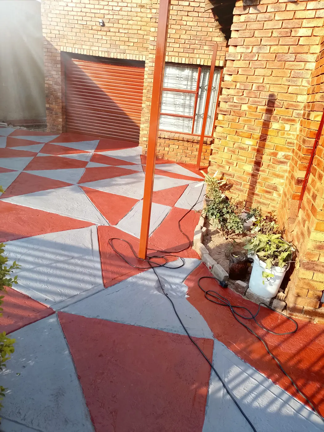 Courtyard paving painted in a red and grey triangle pattern